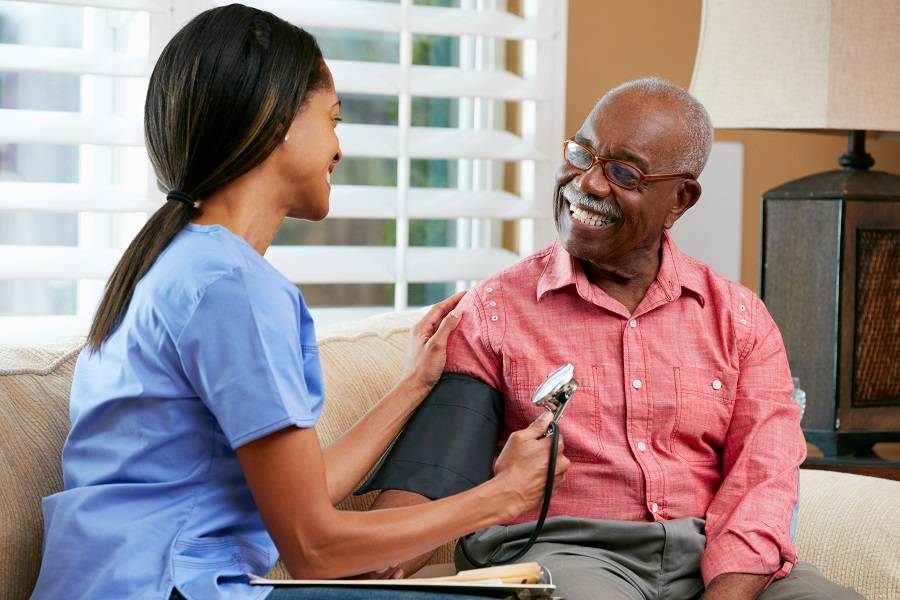 Nurse measuring blood pressure of a senior man at home