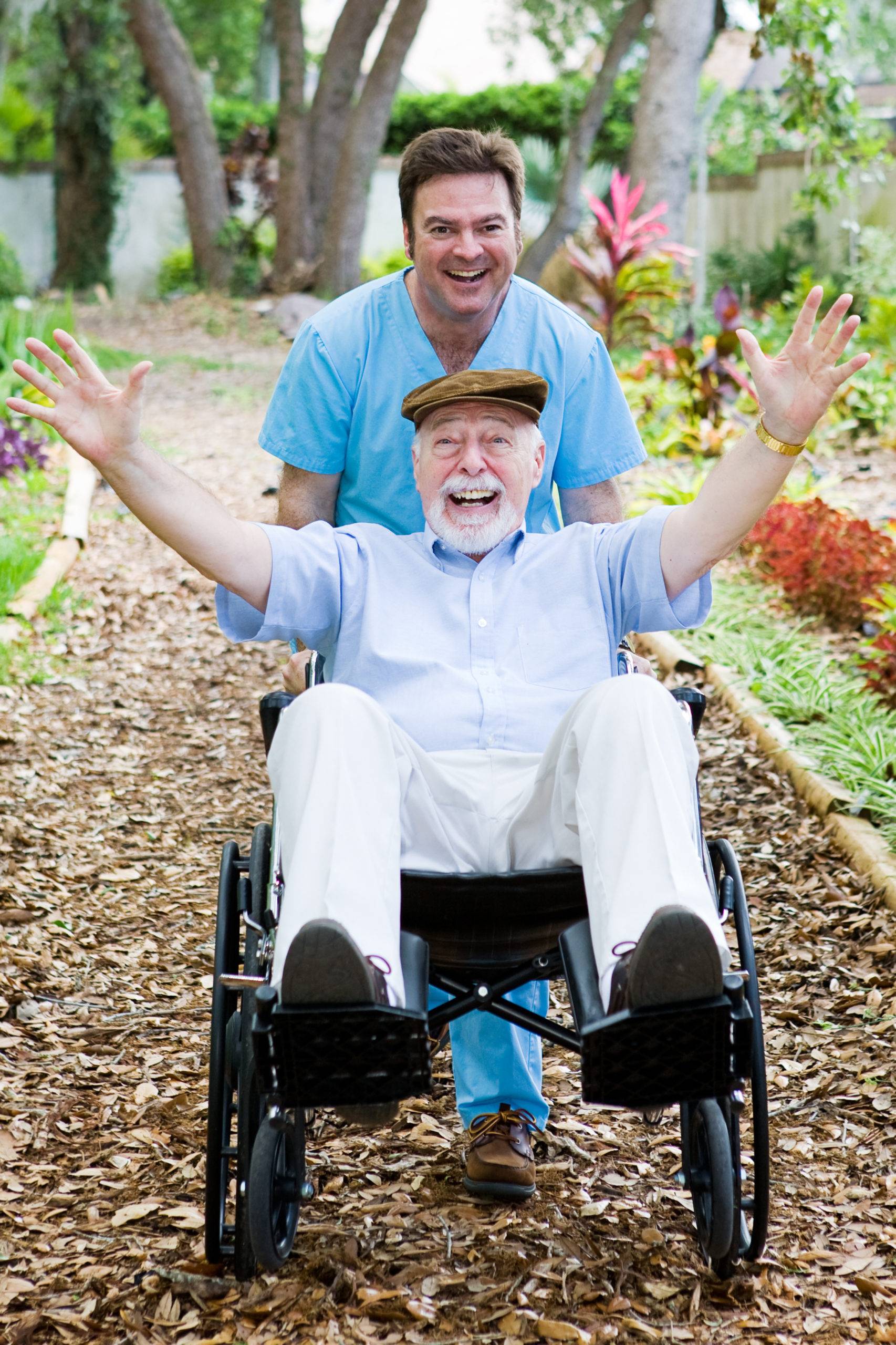 A male caregiver pushing a senior on wheelchair both having fun