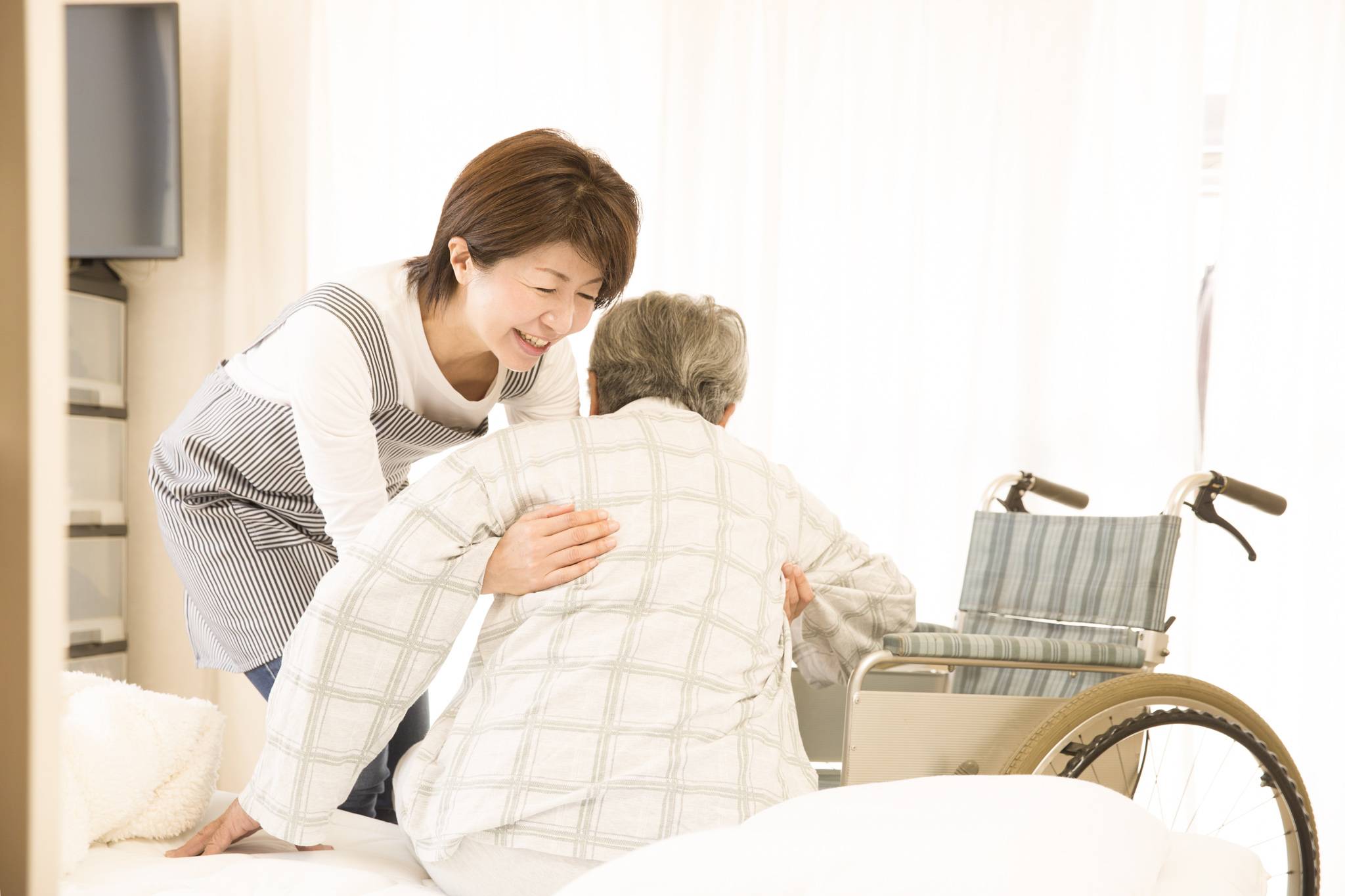 a caregiver helping a senior getting up from bed