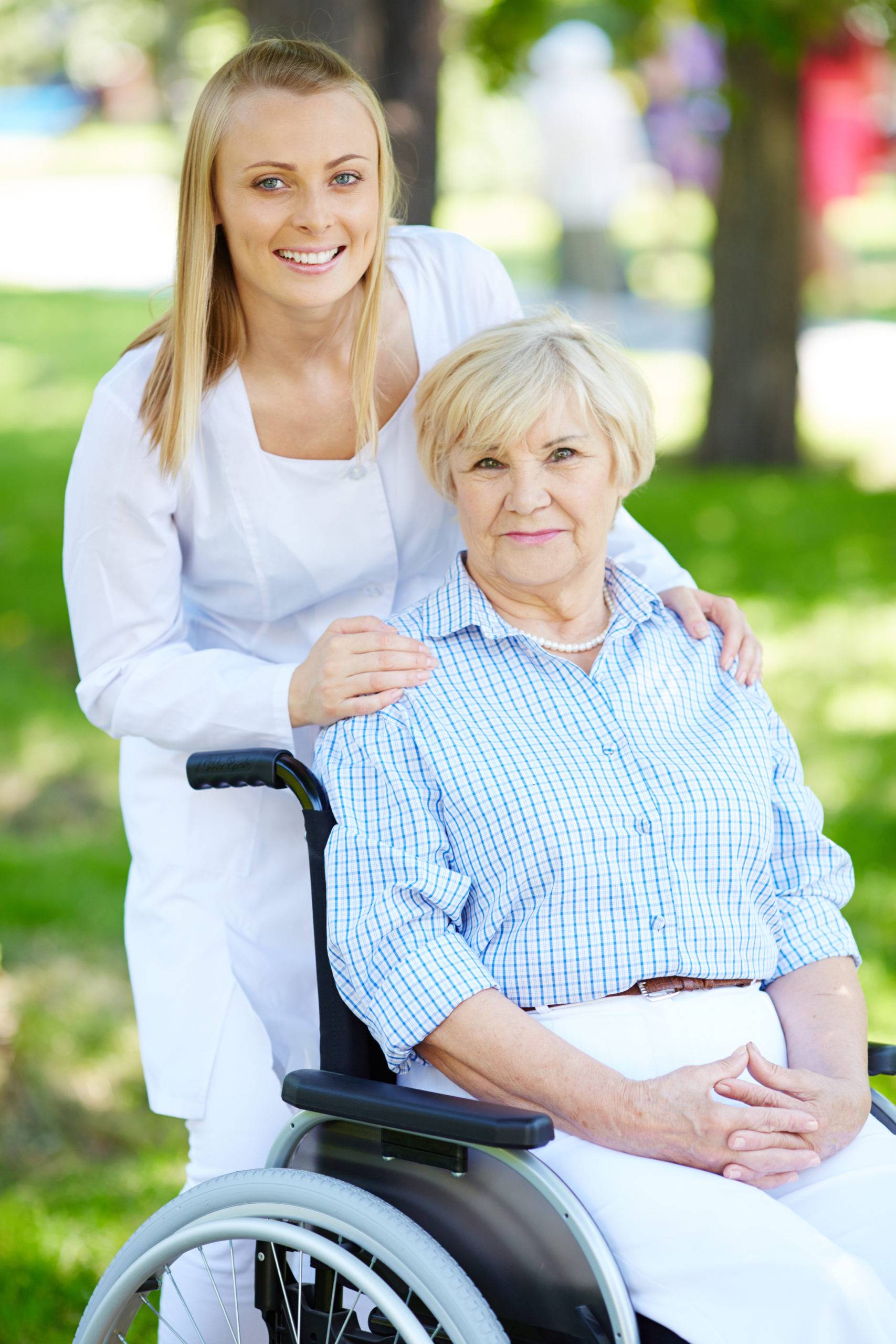 A nurse behind an elderly woman sitting on a wheelchair